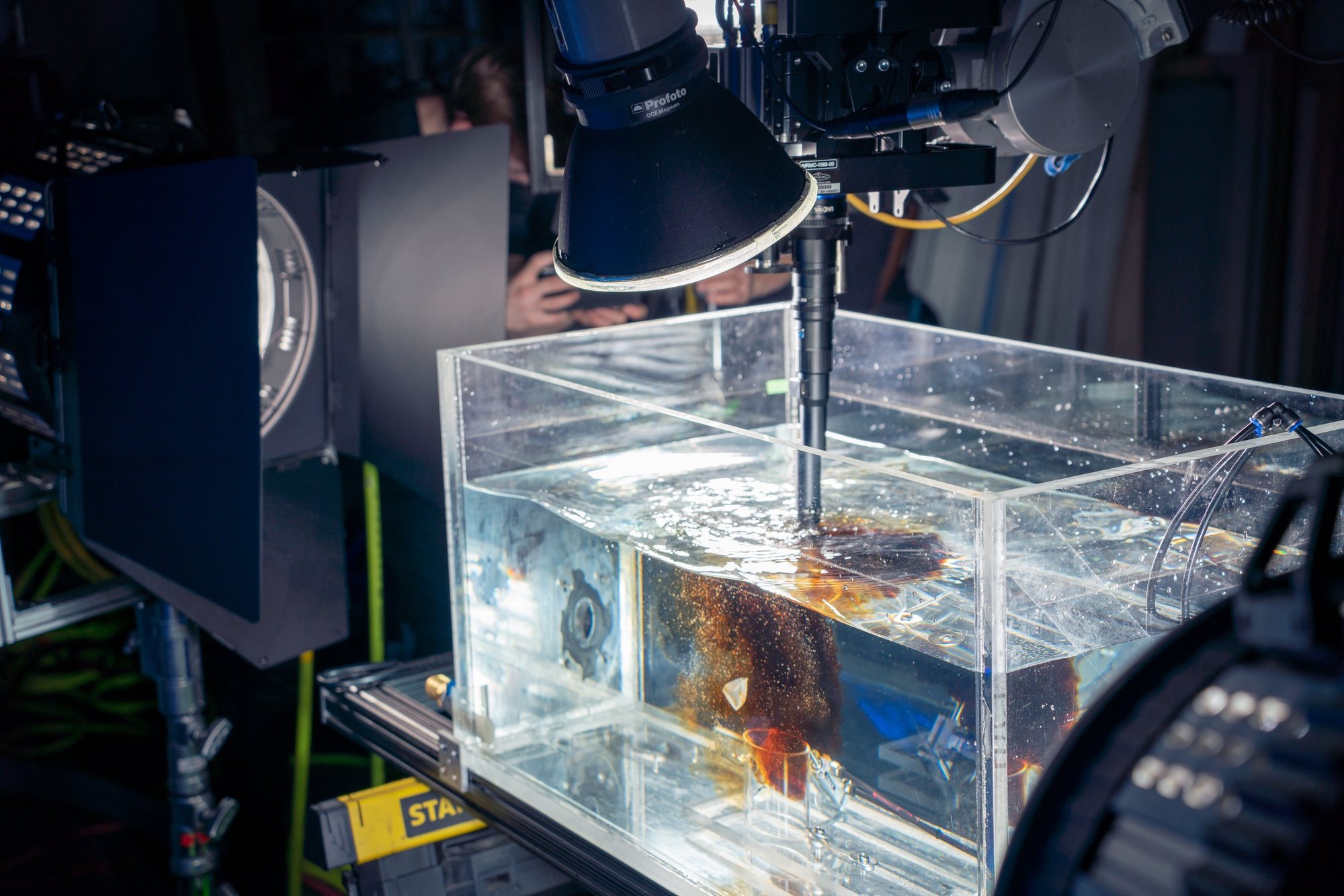 A rig firing cola into a glass tank under studio lights